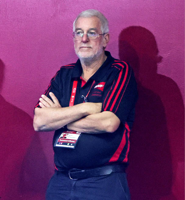 A man wearing a black shirt and glasses stands with his arms crossed. AI generated content