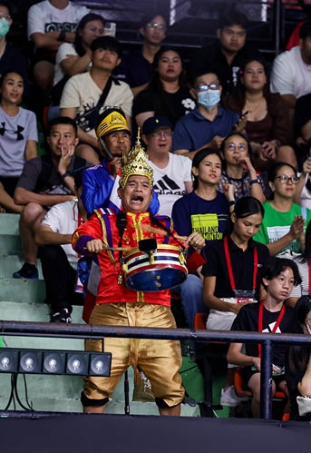 A man in a gold and red costume stands on a stage in front of a crowd of people. AI generated content