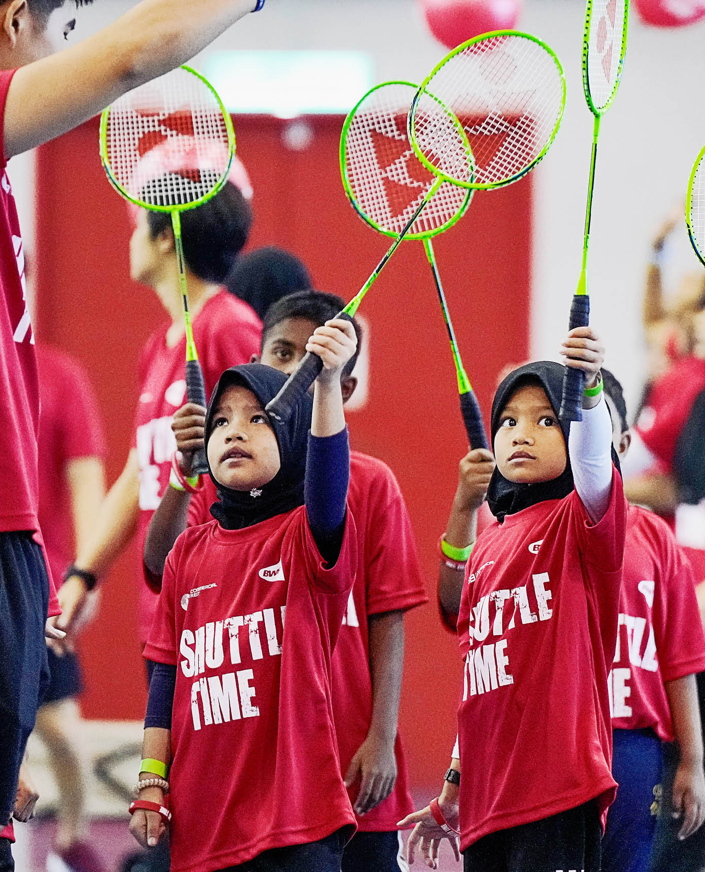 A group of children wearing red shirts are holding tennis rackets. AI generated content