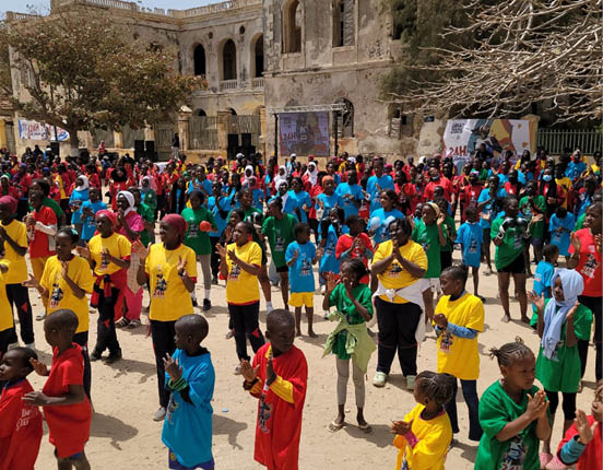 A large group of children wearing colorful shirts are gathered in a courtyard. AI generated content
