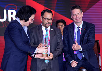 Three people are standing on a stage, holding an award. They are wearing suits and ties, and one of the men is holding a trophy. The other two people are smiling and appear to be enjoying the moment. AI generated content