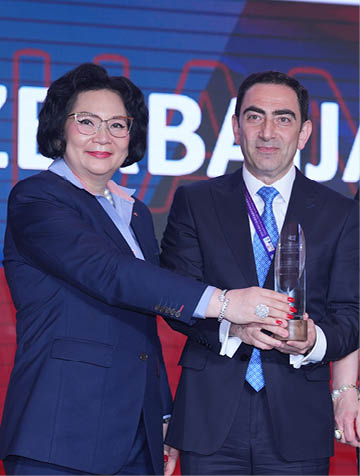 Three people are standing on stage, holding awards. A man and a woman are holding a trophy, while a man in a suit holds a certificate. They are all smiling for the camera. AI generated content
