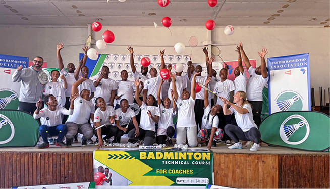 A group of people are standing in front of a banner for Badminton. AI generated content