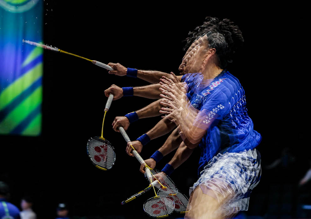 A man in a blue shirt is holding a tennis racket in his hands. AI generated content